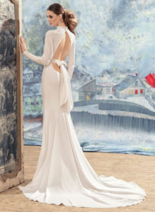 Style #1733La, open back sheath wedding dress with crystals on the high neckline, long sleeves and bow back belt, available in ivory
