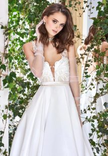 Style #1821L, lace embroidered a-line wedding gown with deep plunging neckline features crisscross spaghetti straps over the low back and satin skirt with pockets, available in ivory