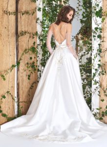 Style #1821L, lace embroidered a-line wedding gown with deep plunging neckline features crisscross spaghetti straps over the low back and satin skirt with pockets, available in ivory