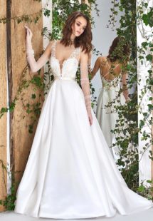 Style #1821L, lace embroidered a-line wedding gown with deep plunging neckline features crisscross spaghetti straps over the low back and satin skirt with pockets, available in ivory