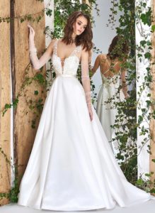 Style #1821L, lace embroidered a-line wedding gown with deep plunging neckline features crisscross spaghetti straps over the low back and satin skirt with pockets, available in ivory