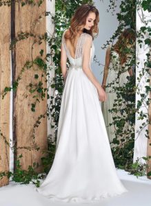 Style #1823L, sleeveless sheath wedding gown with deep plunging neckline features beaded strings over the top, embellished belt, and chiffon skirt, available in ivory