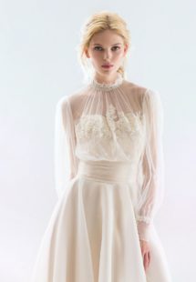 Style #18/1900L, bishop sleeve wedding dress with high neckline and lace embroidery on the bodice, button-up illusion back, and flowy organza skirt, available in ivory