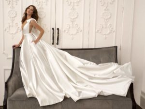 A sleek satin ball gown with a dramatic train and plunging neckline, perfect for brides seeking modern wedding dresses Toronto.