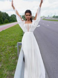 Modern wedding dress with pleated skirt and long cutout sleeves, available in ivory-nude