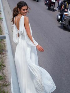 Modern wedding dress with pleated skirt and long cutout sleeves, available in ivory-nude