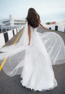 Style #12064, bridal gown with pearl embellishments and cape sleeves, available in ivory