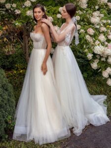 Strapless A-line wedding dress with frilled tulle neckline and a sequinned bodice and A-line wedding dress with bustier style corset, floral decor and pockets; available in ivory-nude, ivory