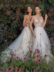 Strapless A-line wedding dress with frilled tulle neckline and a sequinned bodice and A-line wedding dress with bustier style corset, floral decor and pockets; available in ivory-nude, ivory