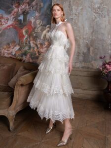 Tea-length A-line wedding dress with a halter neck bodice and a tiered skirt with sequinned embroidery