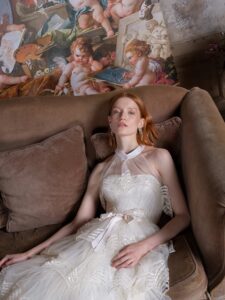 Tea-length A-line wedding dress with a halter neck bodice and a tiered skirt with sequinned embroidery