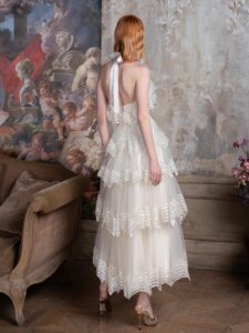 Tea-length A-line wedding dress with a halter neck bodice and a tiered skirt with sequinned embroidery