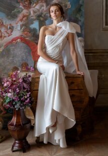 Style #2307L, one-shoulder fitted wedding dress with beading and oversized bow strap; available in ivory