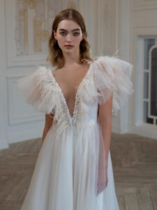 High-low A-line wedding dress with feathers and beads; available in cream