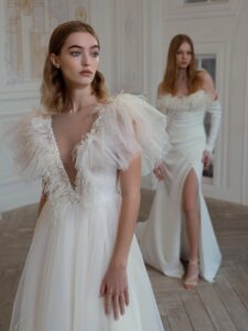 High-low A-line wedding dress with feathers and beads; Draped fitted wedding gown with long sleeves and feather decor