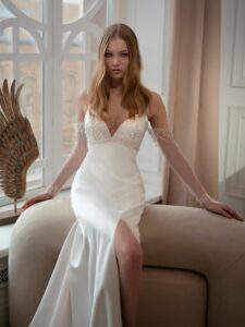Atlas sheath wedding gown with long off-the-shoulder sleeves; available in ivory-peach
