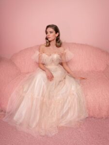 Style #826, shimmering tulle ball gown with ruffled off-the-shoulder neckline and tiered skirt; available in peach (shown online), blue, powder, pink, cornflower blue, green, red, turquoise