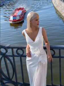 Cocktail-length wedding dress with a plunging V-neckline and a unique side floral appliqué, finished with a skirt tulle panel with pearls