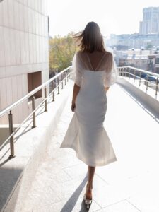 Sheath wedding dress with sheer bishop sleeves and a double slit skirt