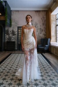 A model wearing an embroidered sheer lace wedding dress with a high neck, featuring intricate lace detailing, by Papilio Boutique bridal store in Toronto.
