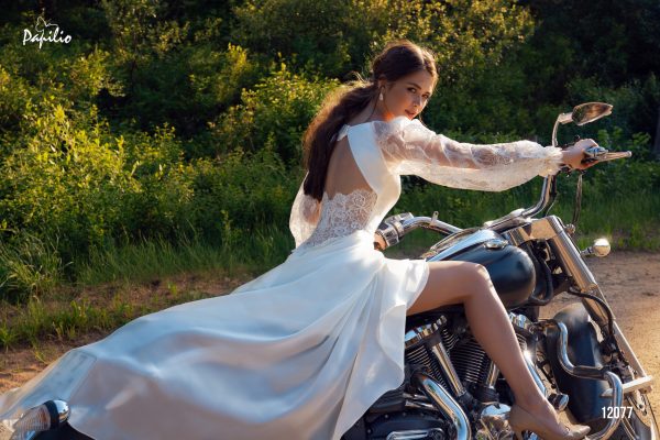 Bride wearing a lace and satin gown with an open back, long sleeves, and flowing skirt, embodying the elegance of Contemporary Wedding Dresses.
