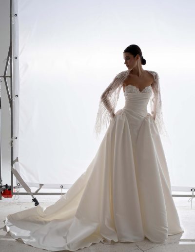 Structured satin ballgown wedding dress with cape by Papilio, photographed in studio, couture satin skirt and beaded cape — Toronto bridal shop.