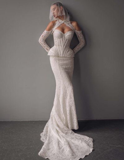 Model wearing a lace two-piece wedding dress with detachable long sleeve bolero and structured semi-sheer corset, captured at Papilio Boutique bridal store in Toronto.