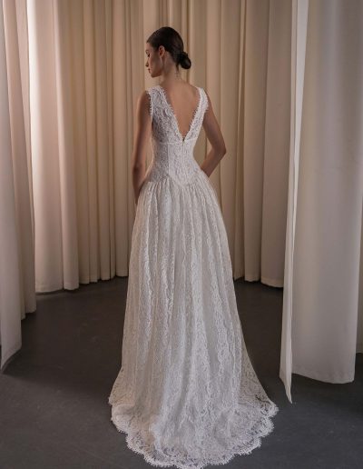 Back view of a lace A-line wedding dress with a deep V-back and scalloped lace train, photographed at Papilio Boutique bridal store in Toronto.
