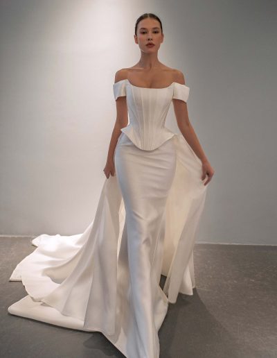 Fit and flare simple off the shoulder wedding dress with basque waist by Papilio Boutique in Toronto.