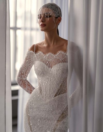 Close-up of shimmering off the shoulder wedding dress with long sleeves by Papilio Boutique, featuring intricate beading and lace details, from a Toronto bridal shop.