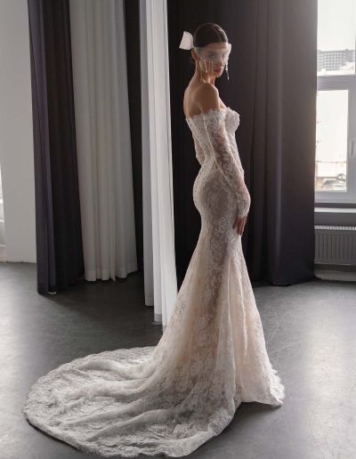 Side profile of lace drop waist fit and flare wedding dress with long sleeves and dramatic train, by Papilio Boutique, Toronto bridal shop.