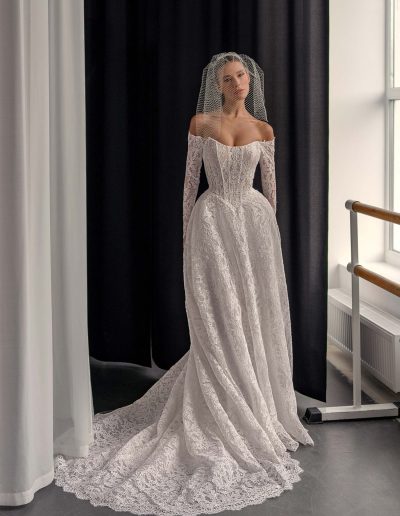 Lace A-line wedding dress with long off the shoulder sleeves and flowing train, offered at Papilio Boutique Toronto.