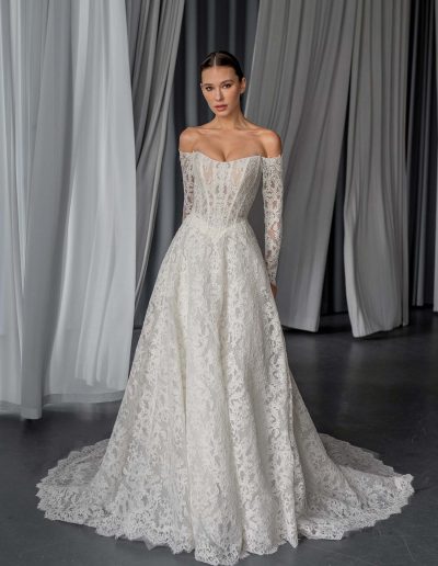 Lace A-line wedding dress with off the shoulder sleeves and basque waist, worn by a model, offered at Papilio Boutique bridal shop Toronto.
