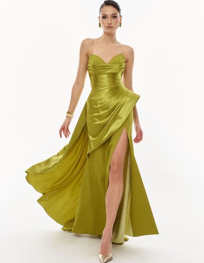 Front view of strapless draped evening gown with sculptural overskirt and high slit, offered at Papilio Boutique.